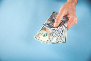 business man's hand holding dollars isolated on blue background