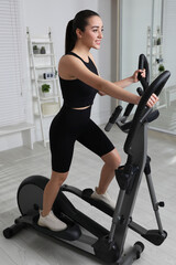 Poster - Happy young woman training on elliptical machine at home