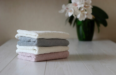 four folded towels of different colors lie on the table against the background of a flower