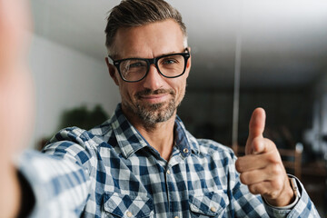 Wall Mural - Happy white-haired man pointing finger at camera while taking selfie
