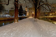 snow-covered evening park alley between two channels