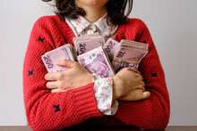 Young Woman Hugging Piles Of Banknotes. Victory And Richness Concept Photo. Happy, Glad And Selfish Lady Loving Her Richness And Does Not Want To Lend. Copy Space On Wall.