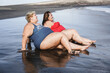 © DisobeyArt - Plus size friends women sitting on the beach having fun during summer vacation - Happy curvy people having fun on the beach - Focus on faces