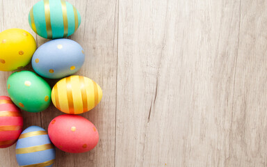 Wall Mural - Colorful handmade painted easter eggs on a wood background.