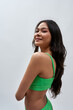© Svitlana - Portrait of proud young woman with slim body wearing green underwear smiling, turning her head to camera while posing isolated over light background