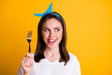 Photo Of Charming Lady Hold Fork Lick Teeth Look Empty Space Wear Blue Headband White T-shirt Isolated Yellow Color Background