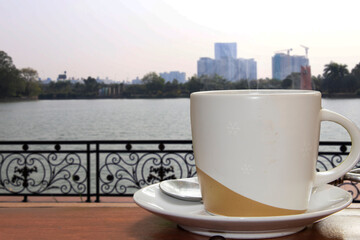 Coffee in a white cup on a wooden table in a cafe with backlight