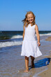 Beautiful girl in a white dress walking on the beach