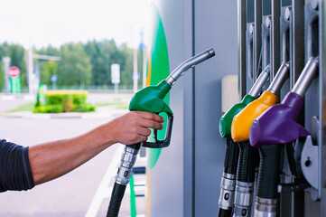 Man holds a refueling gun in his hand for refueling cars. Gas station with diesel and gasoline fuel close-up.