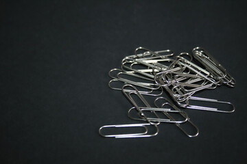 Poster - Pile of metal paper clips on black background