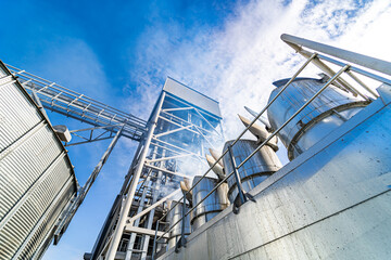 View from below on steel grain elevators. Industrial agriculture elevators with harvested grain. Modern up to date factory. Selective focus.