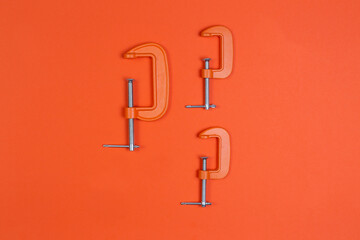 clamp, clamps on an orange background. compress, repair, construction.