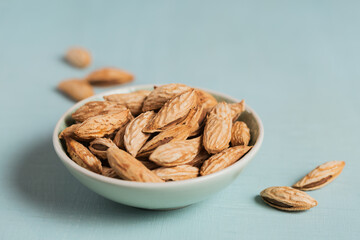 Wall Mural - Pile of Almond nuts in a bowl on a light blue background