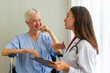 © ake - Caucasian old senior depressed upset woman patient on wheelchair talking to medical doctor with stethoscope  in hospital