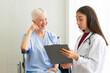 © ake - Caucasian old senior depressed upset woman patient on wheelchair talking to medical doctor with stethoscope  in hospital