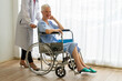 © ake - Caucasian old senior depressed upset woman patient on wheelchair talking to medical doctor with stethoscope  in hospital