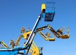 © luca piccini basile - Blue and yellow aerial work platform against clear blue sky