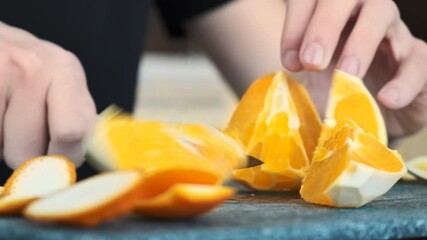 Wall Mural - A man slicing an orange on a cooking board using a knife