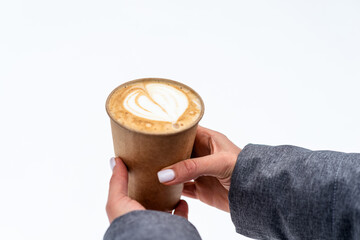 Girl holding a glass of cappuccino over the snow close-up.