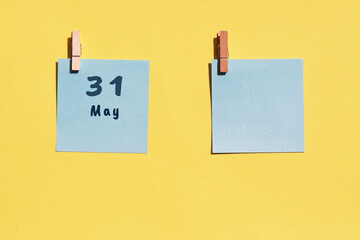 May 31st . Day of 31 month, calendar date. Two blue sheets for writing on a yellow background. Top view, copy space. Spring month, day of the year concept