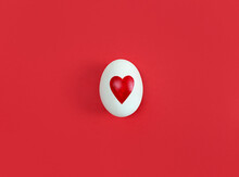 White Egg With Heart Shape On Red Background.