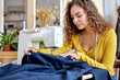 young tailor working on sewing machine, hand making clothes in home interior. caucasian curly female sits enjoying process of sewing clothes. creative skills design, hobbies and lifestyle concept