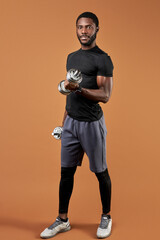 black skinned male posing with dumbbells, wearing sportive clothes, looking at camera, isolated