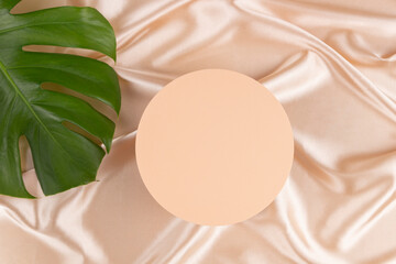 Wall Mural - Geometric platform podium and monstera leaf on pastel silk satin background. Blank minimal round cylinder form mock up background for cosmetic product presentation. Top view