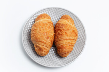 Close-up of two croissants in grey plate on white background.