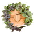 .Round cutting board with wooden heart in centre. Various sweet basil herb leaves edged.. Healthy food concept. Top view..