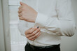 Closeup of a stylish and elengant man adjusting the cufflink on his white formal shirt