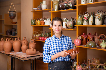 Wall Mural - Positive female artisan having ceramics in workshop. High quality photo