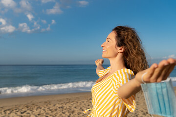 Poster - Happy woman wearing medical mask outdoor against blue sea and sky background