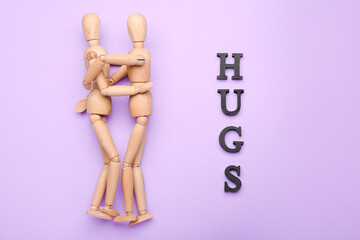 Wall Mural - Wooden mannequins with word HUGS on color background