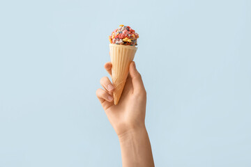 Woman holding waffle cone with popcorn ball on color background