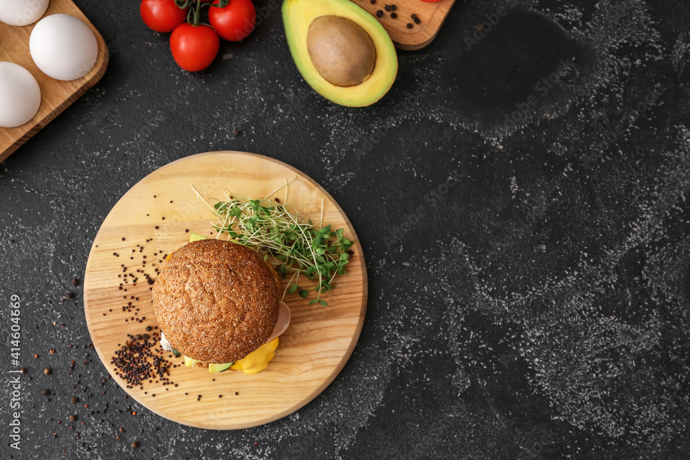 Tasty burger with florentine egg and fresh vegetables on dark background