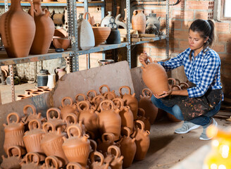 Wall Mural - Woman chooses pots clay pots in store warehouse. High quality photo