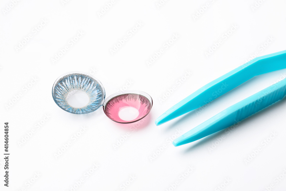 Tweezers with color contact lenses on white background