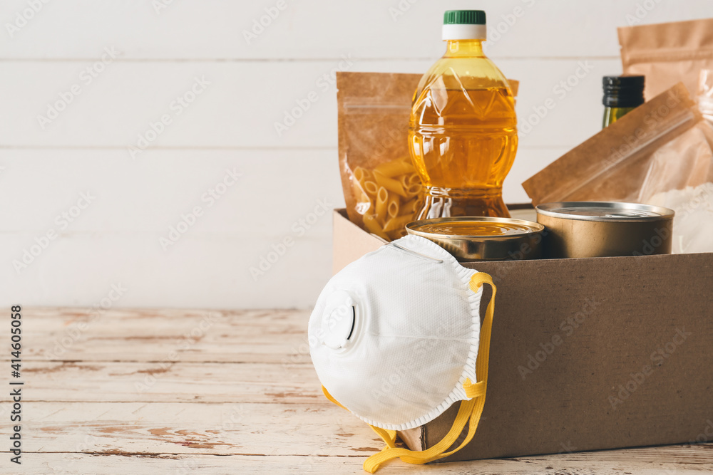 Box with different products and respirator on wooden background