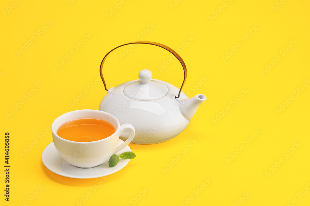 Stylish teapot and cup of tea on color background