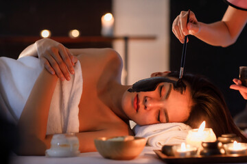 Masseurs hand do holding glass and brushing a facial mask herb black cream to on customer's face as sleep and covered warp by a white on her body