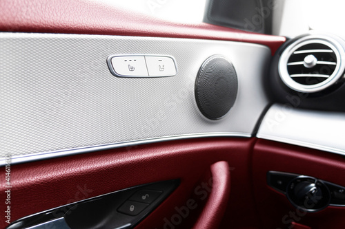 Car door handle inside the luxury modern car with red leather texture with stitching. Switch button control. Modern car interior details. Red perforated leather
