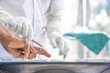 © Kampan - A doctor in white clothes, wearing white anti-germ gloves, is cleaning the wound on a person's finger caused by a cut knife