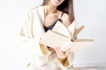 Beautiful smiling woman in comfortable home clothes reading a book sitting on the floor