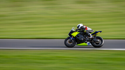 Wall Mural - A panning shot of a racing motorbike as it circuits a track.