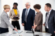 © chagin - Group of multi-ethnic business people standing around the office desk and discussing the project