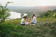 © eduard - Friends interacting while having picnic on the hill on a sunny summer day. Friends drinking wine.