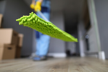 Wall Mural - Worker holds mop with green rag for floor. Services of cleaning company concept