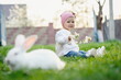 © Oleksandr - Cute little girl in green grass on a sunny day. Happy baby on the background of rabbits in the park. Portrait of one year old baby outdoors.