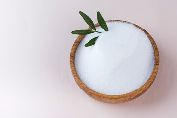 Natural sweetener in a wooden bowl on a pink background. Sugar substitute. Erythritol. Copy space.